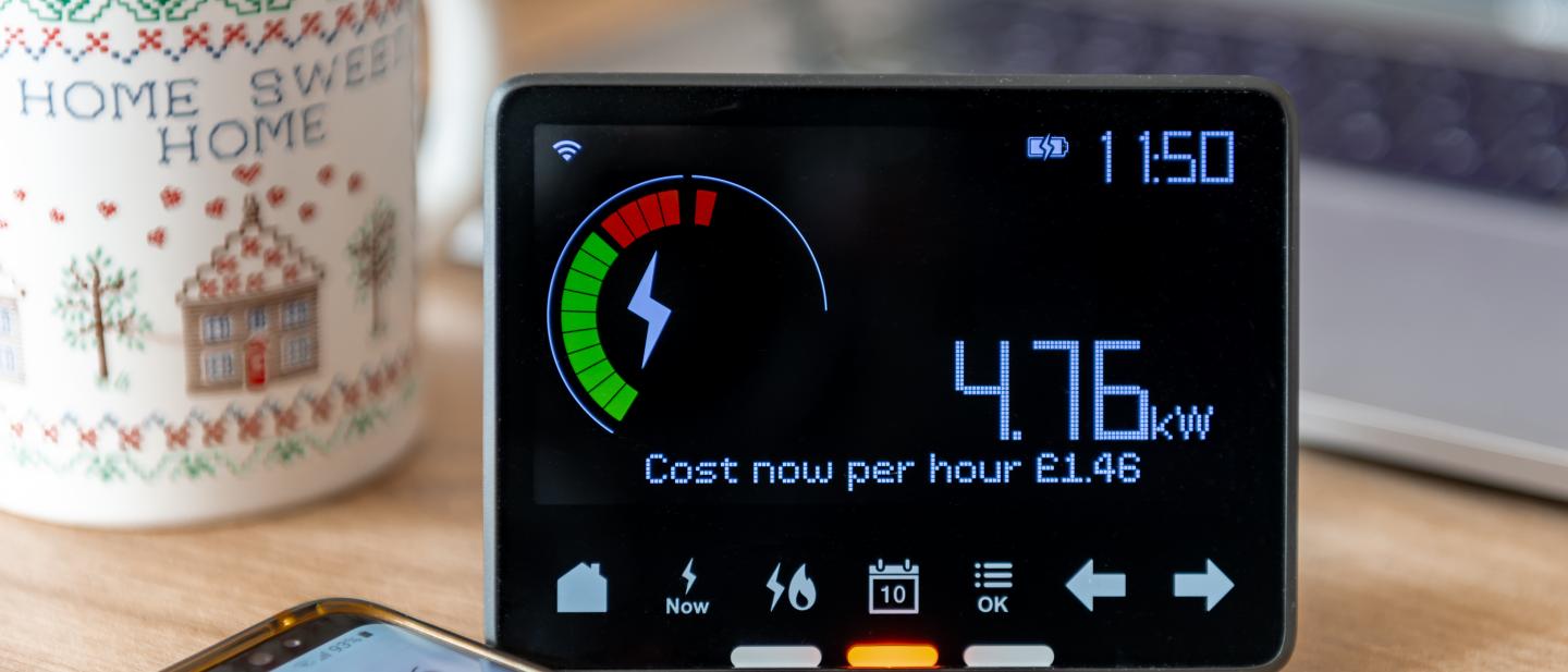 Home energy monitor next to a mug on a table top.